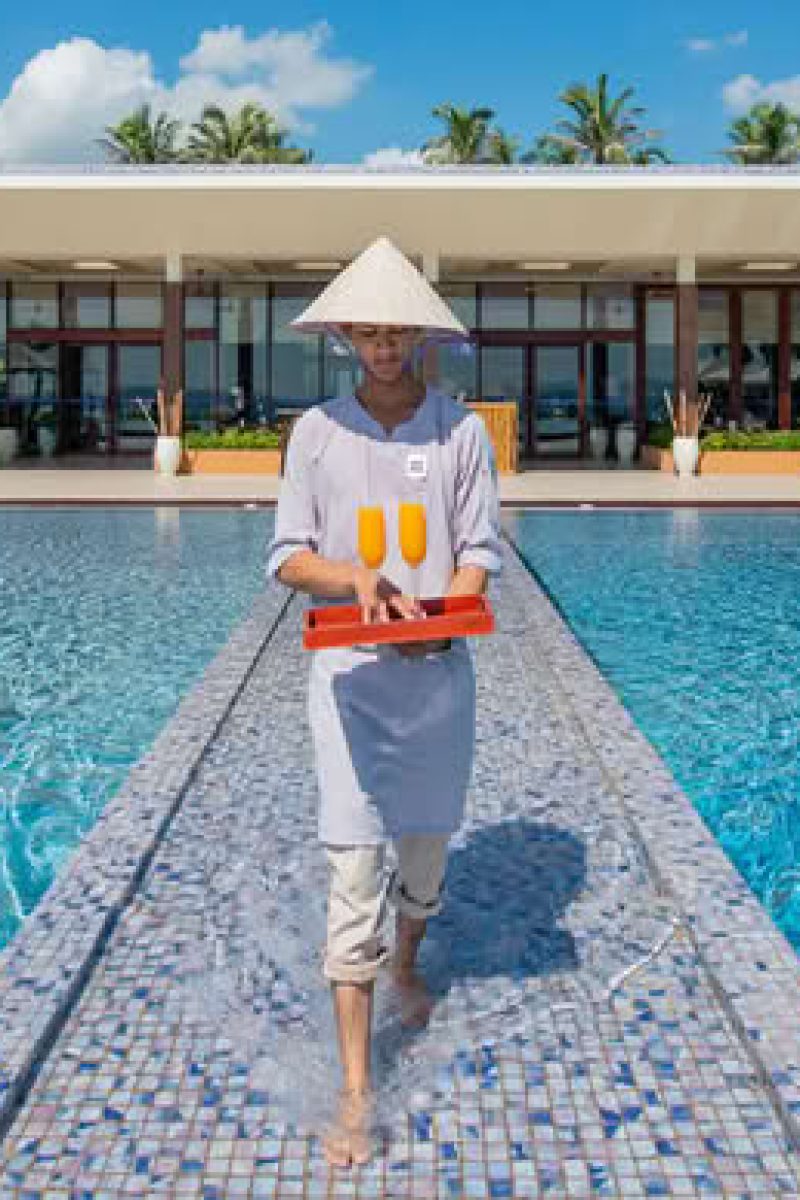 Resort staff serving drinks through infinity pool by Tonkin Legends