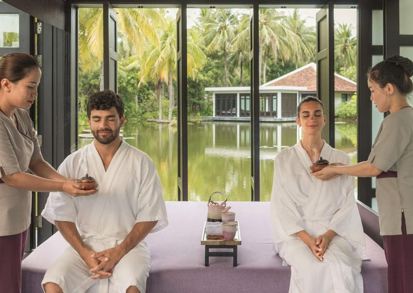 Couple enjoying a pre-treatment ritual with therapists offering herbal bowls at Four Seasons The Nam Hai spa