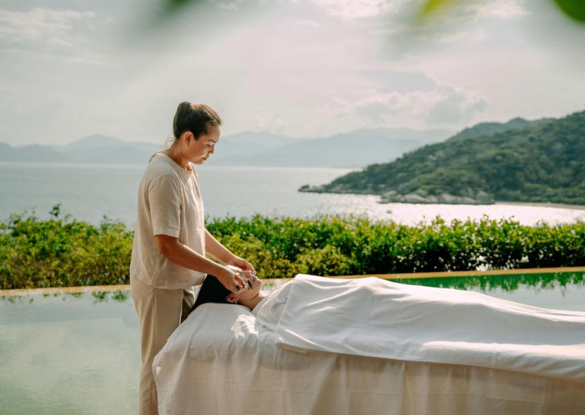 Outdoor spa massage treatment at Six Senses Ninh Van Bay with a therapist working poolside
