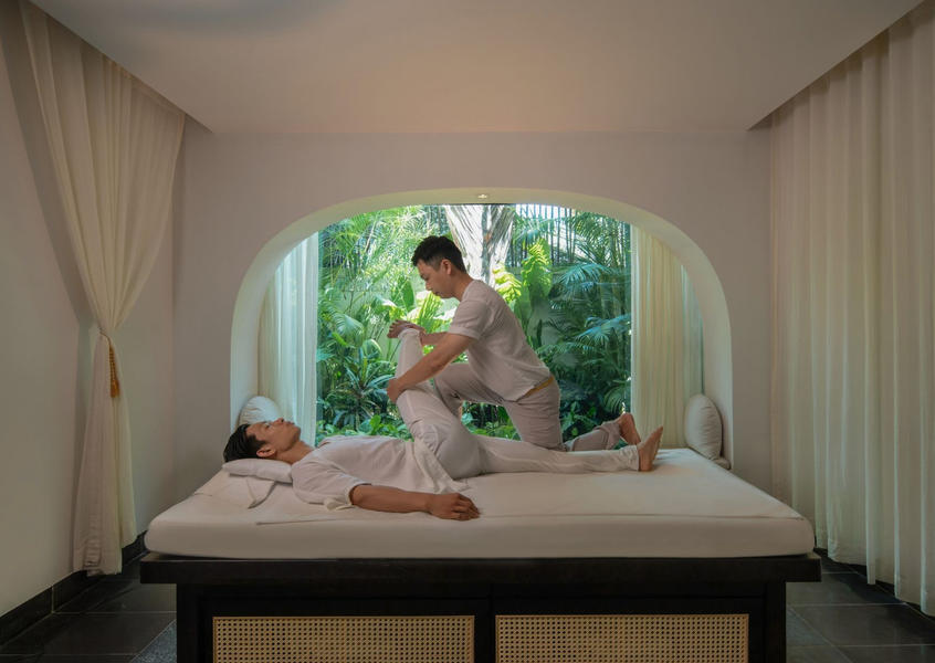 Thai-style stretch massage treatment inside a serene spa room at TIA Wellness Resort Da Nang