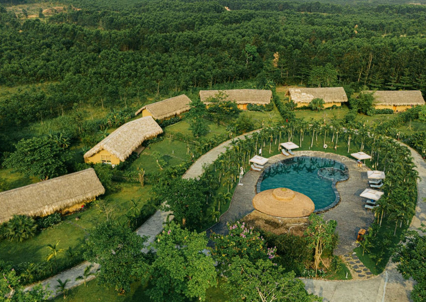 Aerial view of Alba Wellness Valley thatched villas and pool in Hue forest