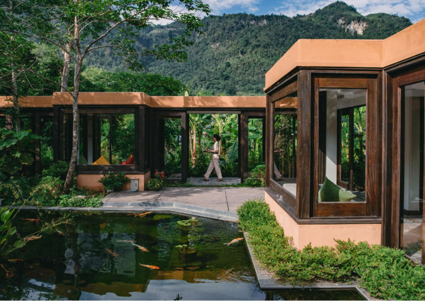 Glass villa and koi pond at Avana Retreat with mountain forest backdrop