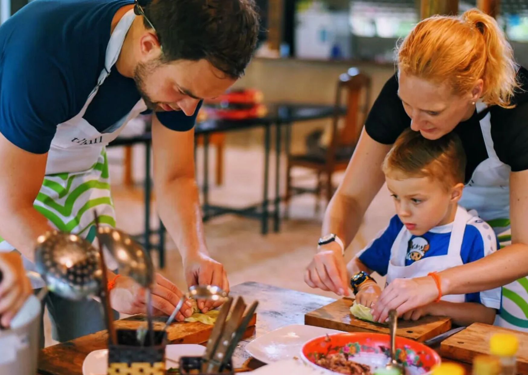 Family with a child preparing fresh ingredients together during a Vietnamese cooking class
