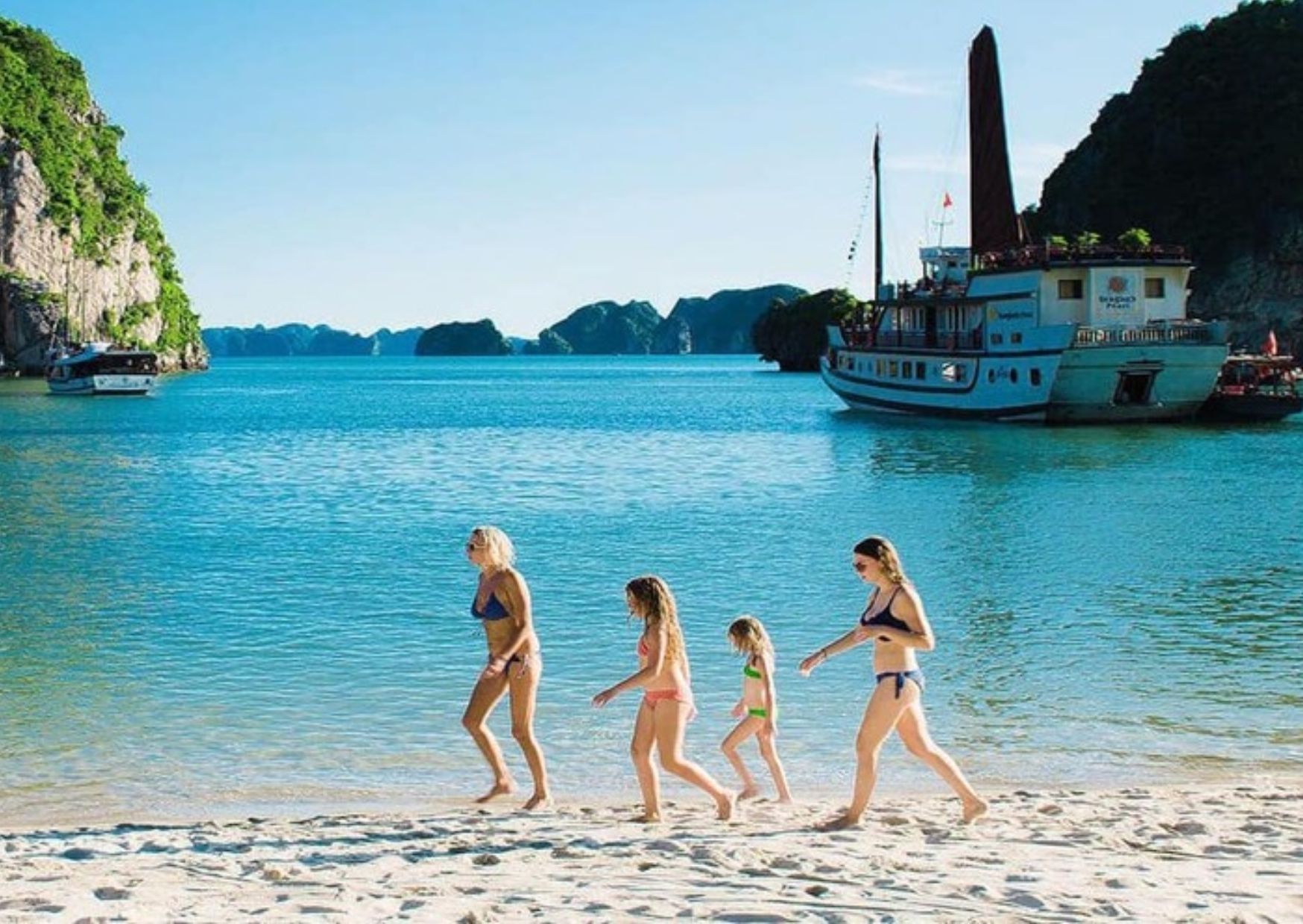 A family wandering around the idyllic sand beach on Ha Long Bay