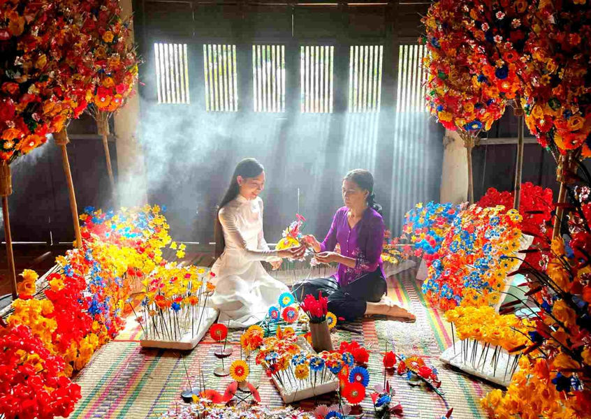 Two women making traditional paper flowers at Hue craft village Vietnam