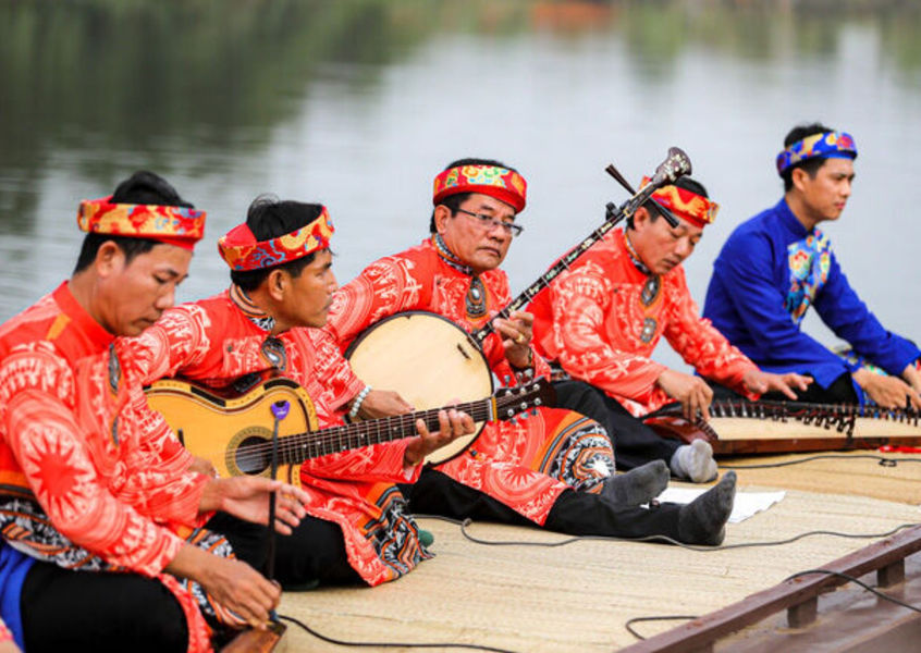 Traditional Vietnamese folk musicians in red costumes performing on river boat Mekong Delta