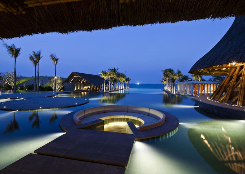 Naman Retreat Da Nang illuminated pool and bamboo pavilions at dusk