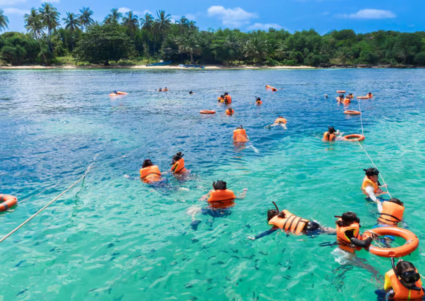 Group of tourists snorkeling in clear turquoise water off the coast of Phu Quoc Island