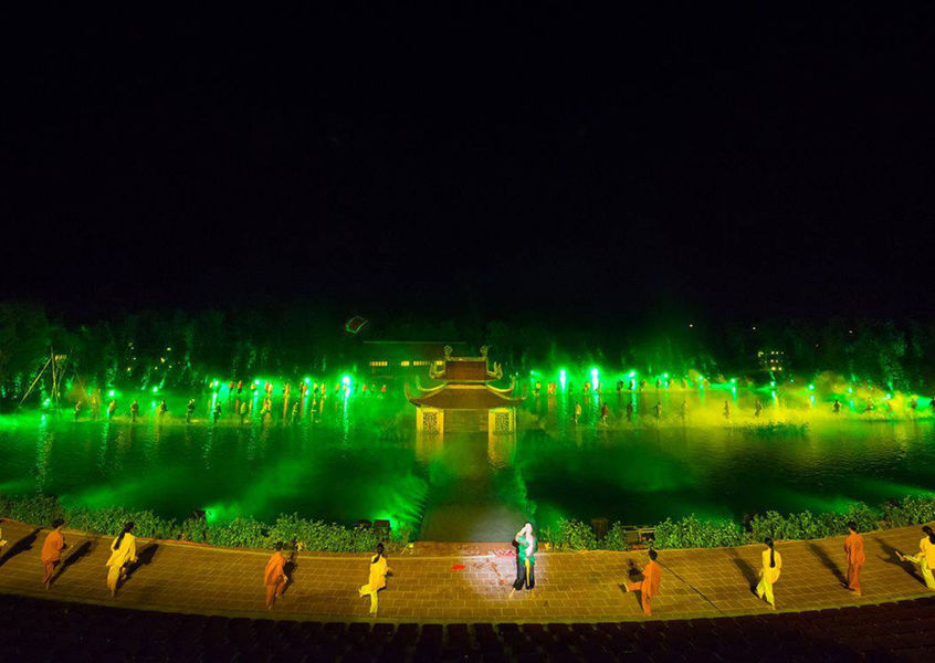 Outdoor water stage cultural performance with green lights at night Vietnam