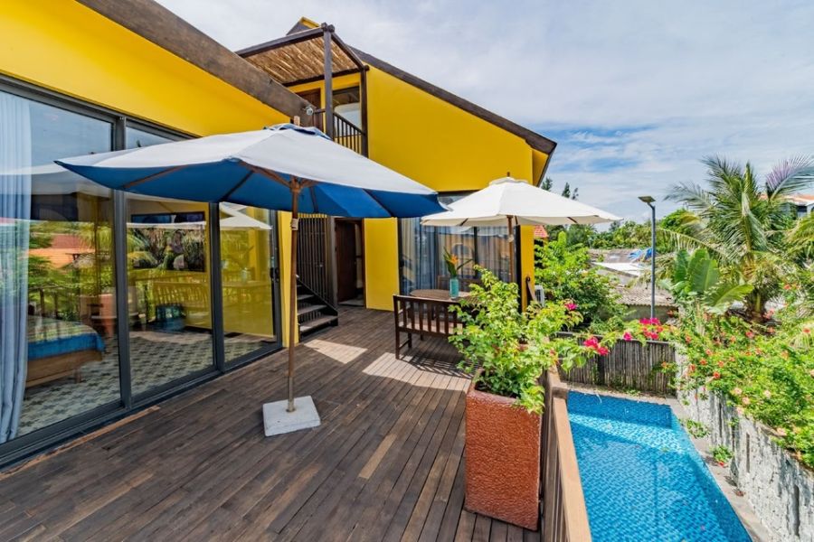 Wooden terrace with small plunge pool beside yellow villa