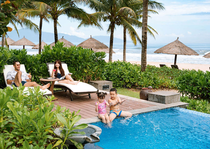 Family relaxing poolside with beach view at Danang Marriott