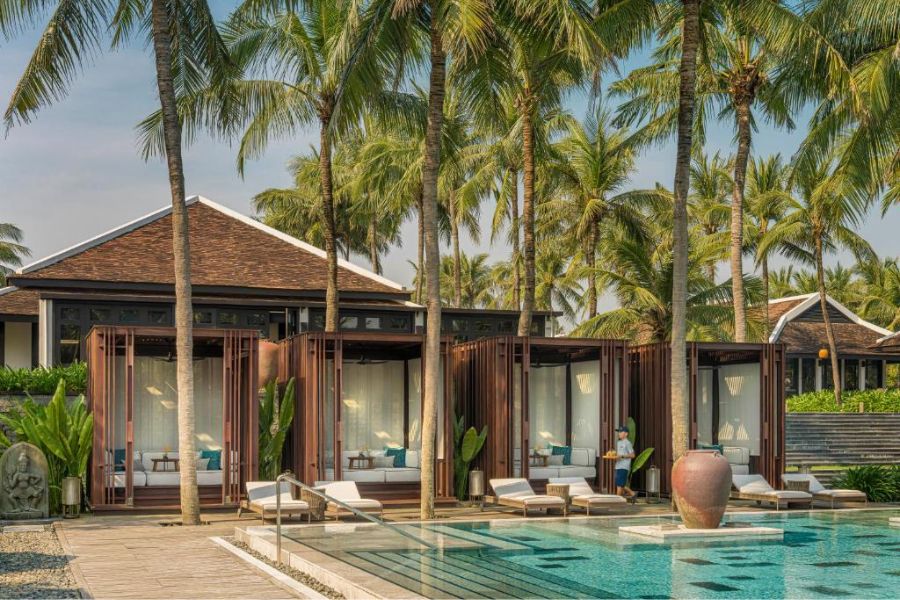 Wooden pool cabanas surrounded by palm trees at beachfront resort