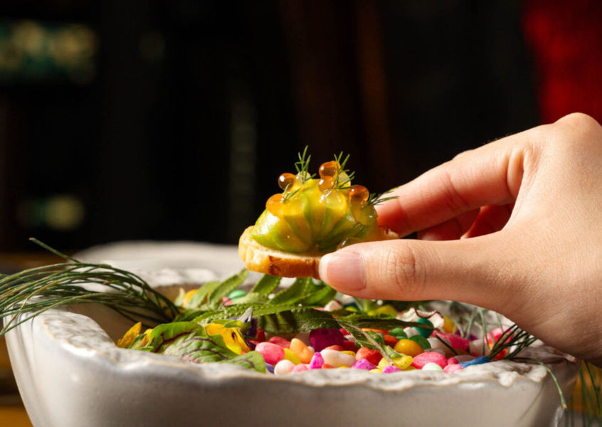 Hand holding a garnished canape with caviar at InterContinental