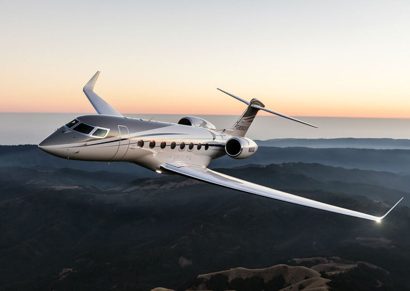 Private jet flying over coastline at sunset