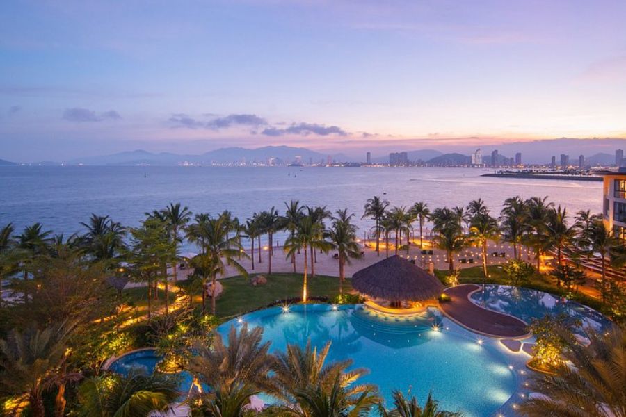 Aerial dusk view of resort swimming pools with the Nha Trang coastal skyline in the distance
