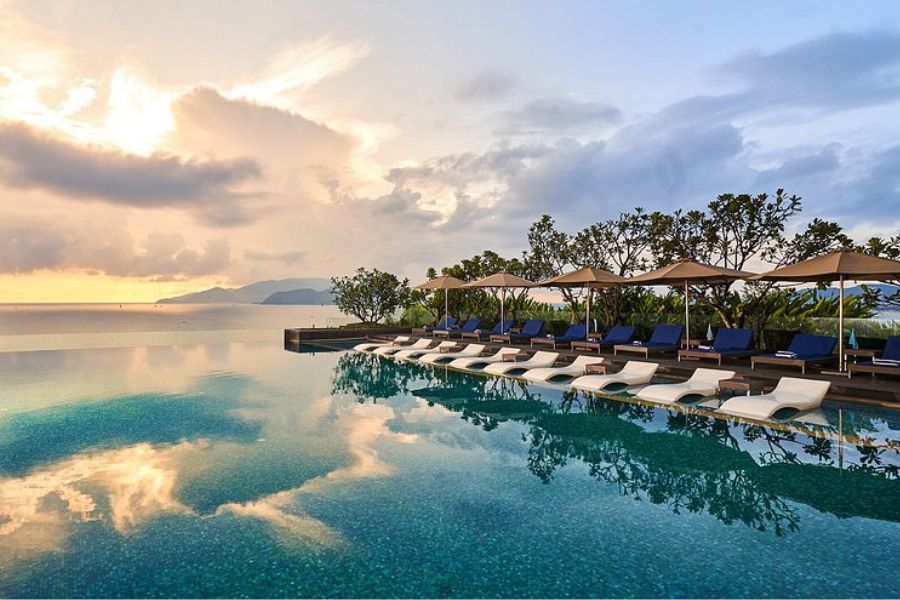 Infinity pool deck with lounge chairs at sunset overlooking the sea in Nha Trang