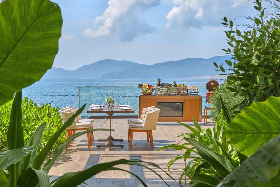 Outdoor dining terrace overlooking the sea and mountains at a boutique beachfront hotel