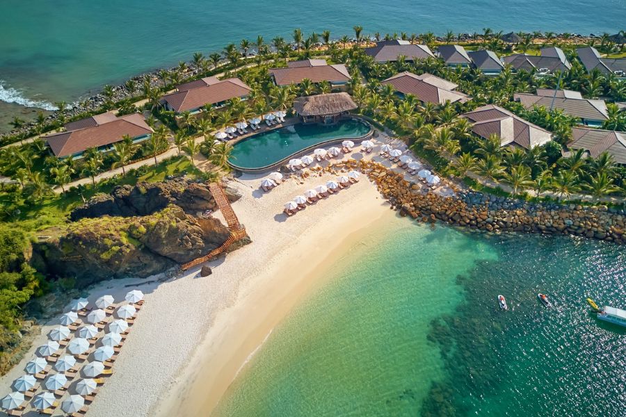 Aerial view of a private cove beach with a pool and bungalows at a hillside resort near Nha Trang