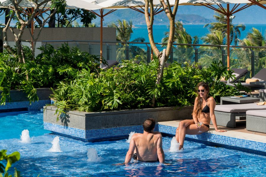 Guests relaxing in a rooftop jacuzzi pool overlooking the Nha Trang coastline