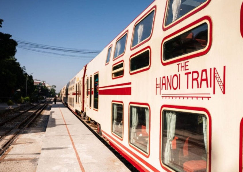 Exterior side view of The Hanoi Train double-decker carriage parked at the station platform