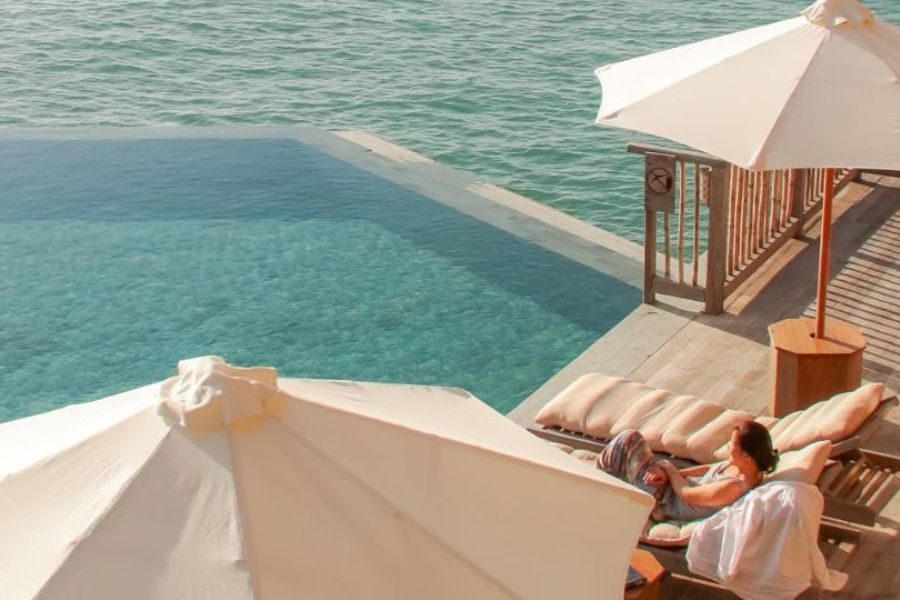 Vietnam luxury travel: guest relaxing by overwater infinity pool
